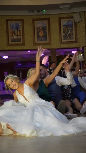 A bride on the floor with her guests, arms up