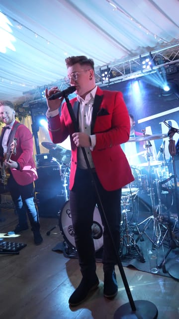 Adam singing on stage in a red jacket