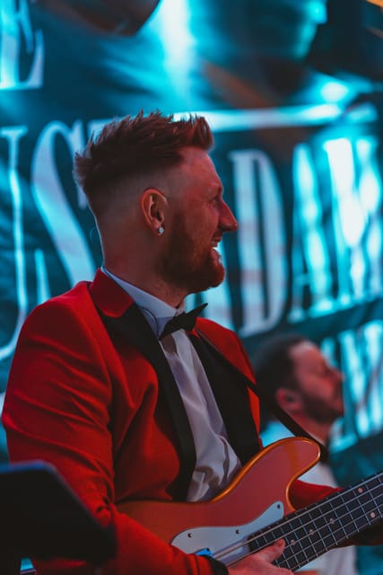 The bass player in a red jacket, laughing