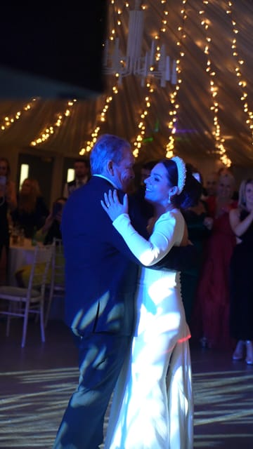 A couple dancing under a marquee of lights
