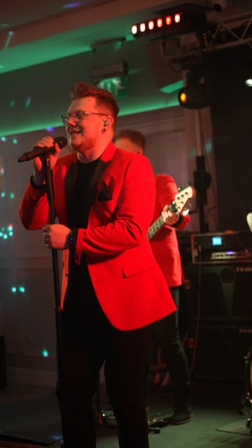 Adam smiling at the microphone with the band behind him