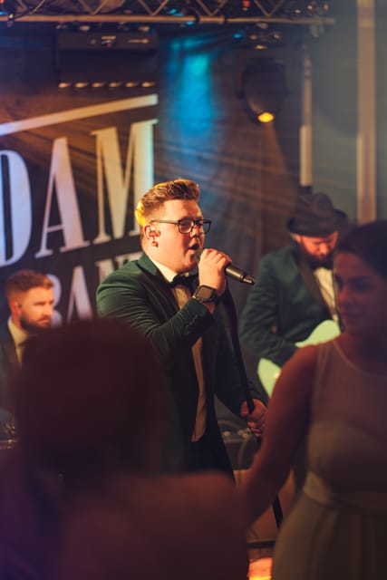 Adam singing in a blue tuxedo with the band