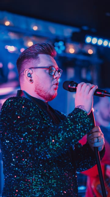 Adam singing in a green sequin jacket