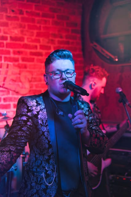Adam at the microphone in a black and gold jacket