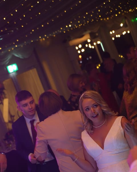 A bride smiling on a busy dance floor at Beech Hill