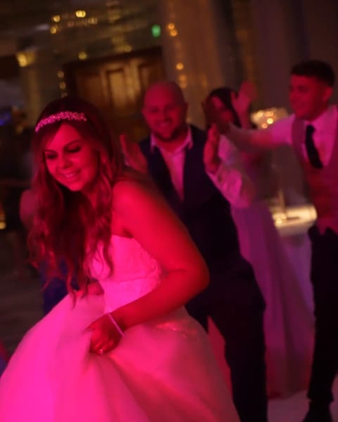 A bride dancing under pink light at Culloden