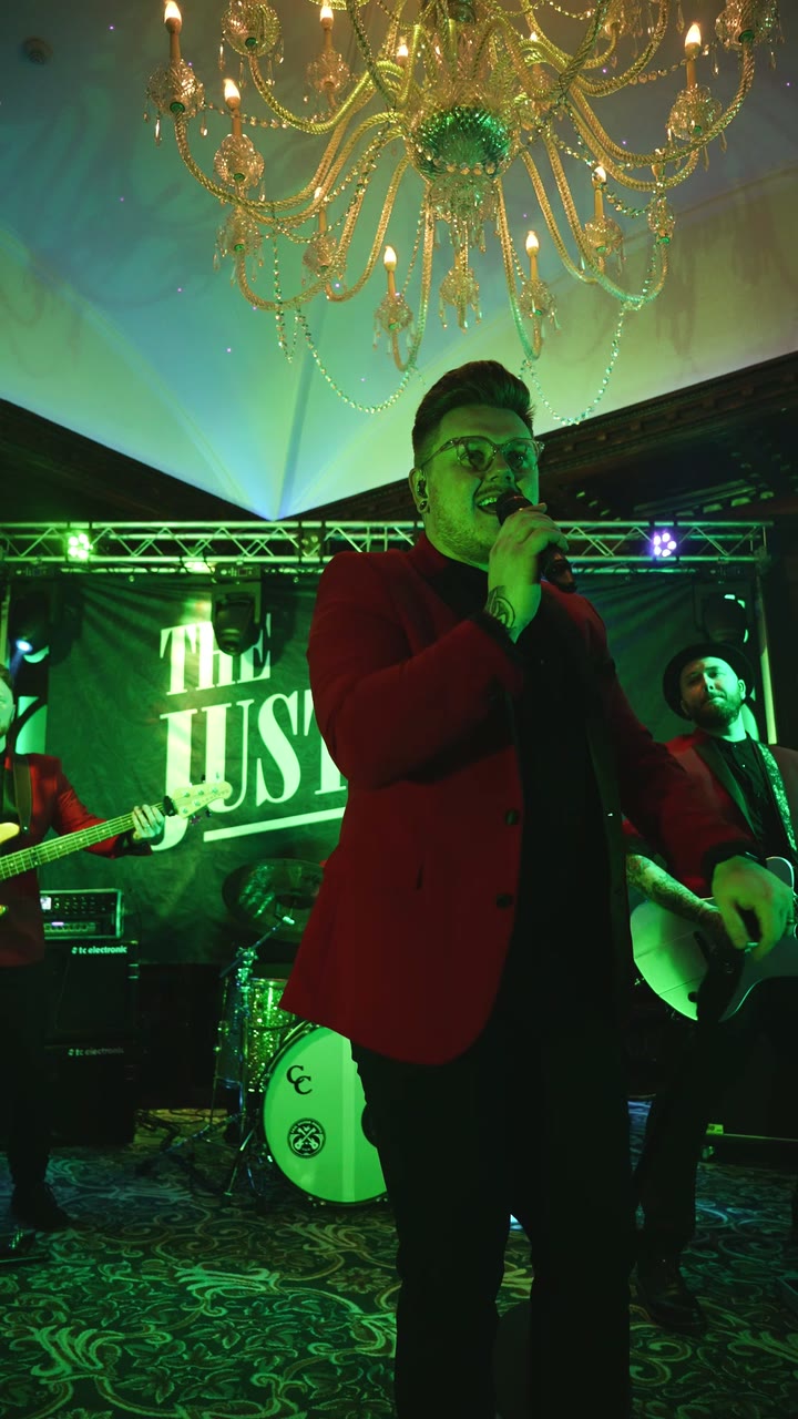 Adam singing in a red jacket in front of the band backdrop at Cabra Castle